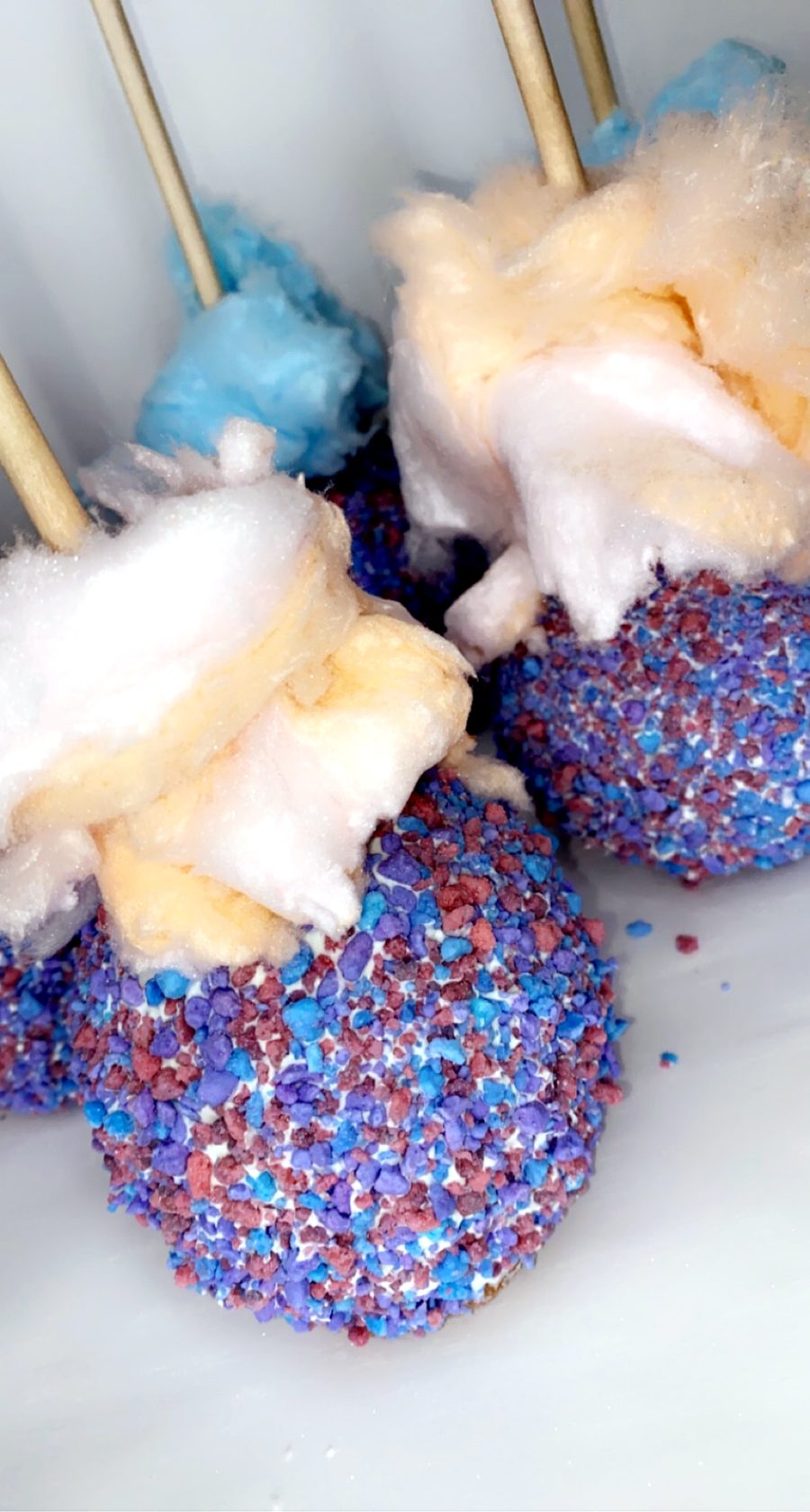 Cotton candy apples in blue, purple and pink with cotton candy tufts