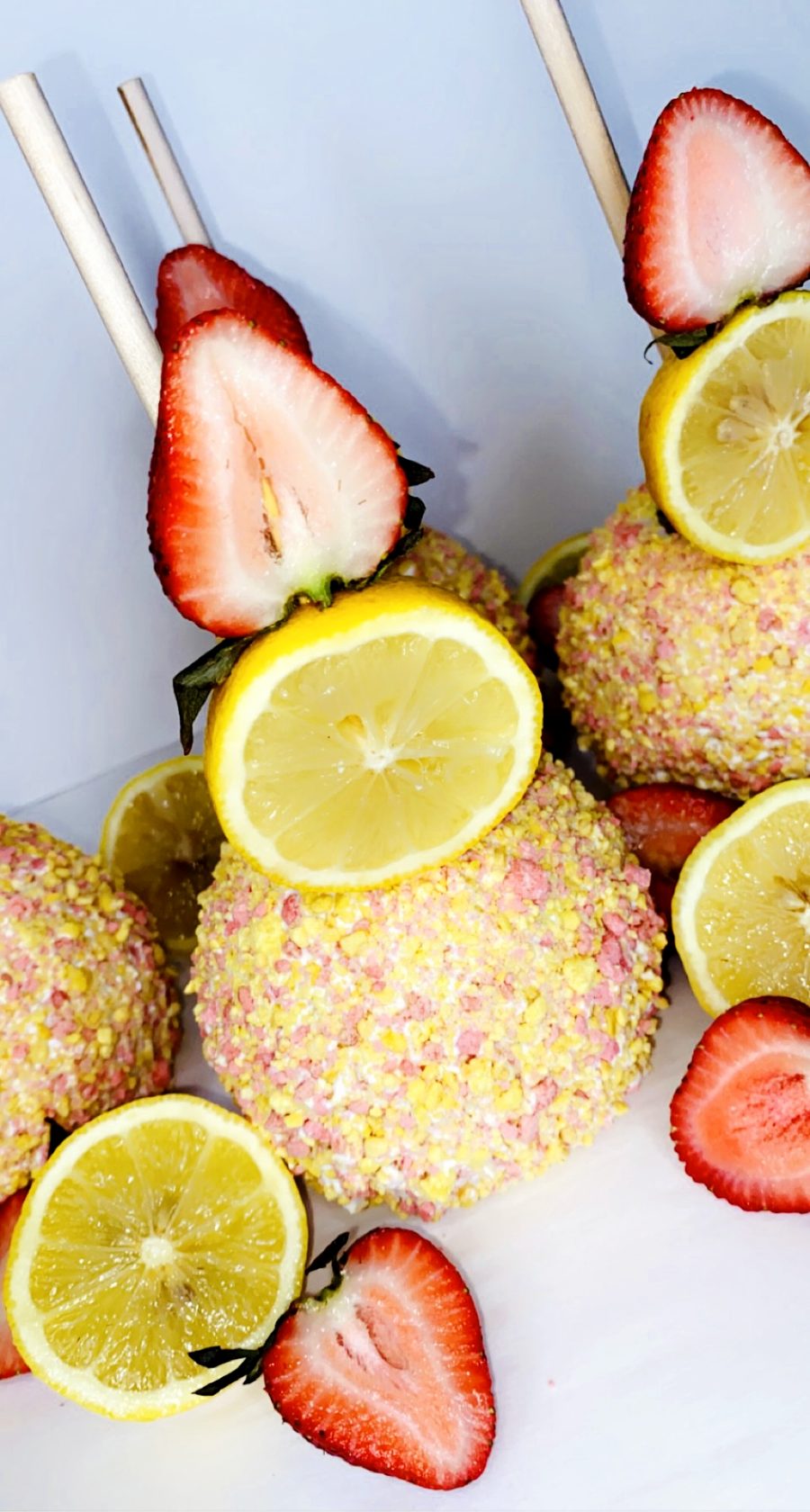 Strawberry lemonade candy apples topped with a lemon wheel and fresh strawberry