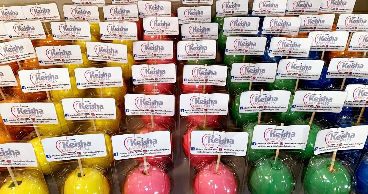 Trays of individually packaged candy apples in red, yellow, orange, green and blue, each labelled and ready to sell
